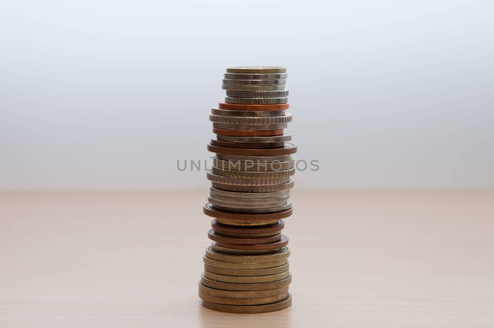 A stack of coins of different countries, different dignity, and size on the table in the center of the image.