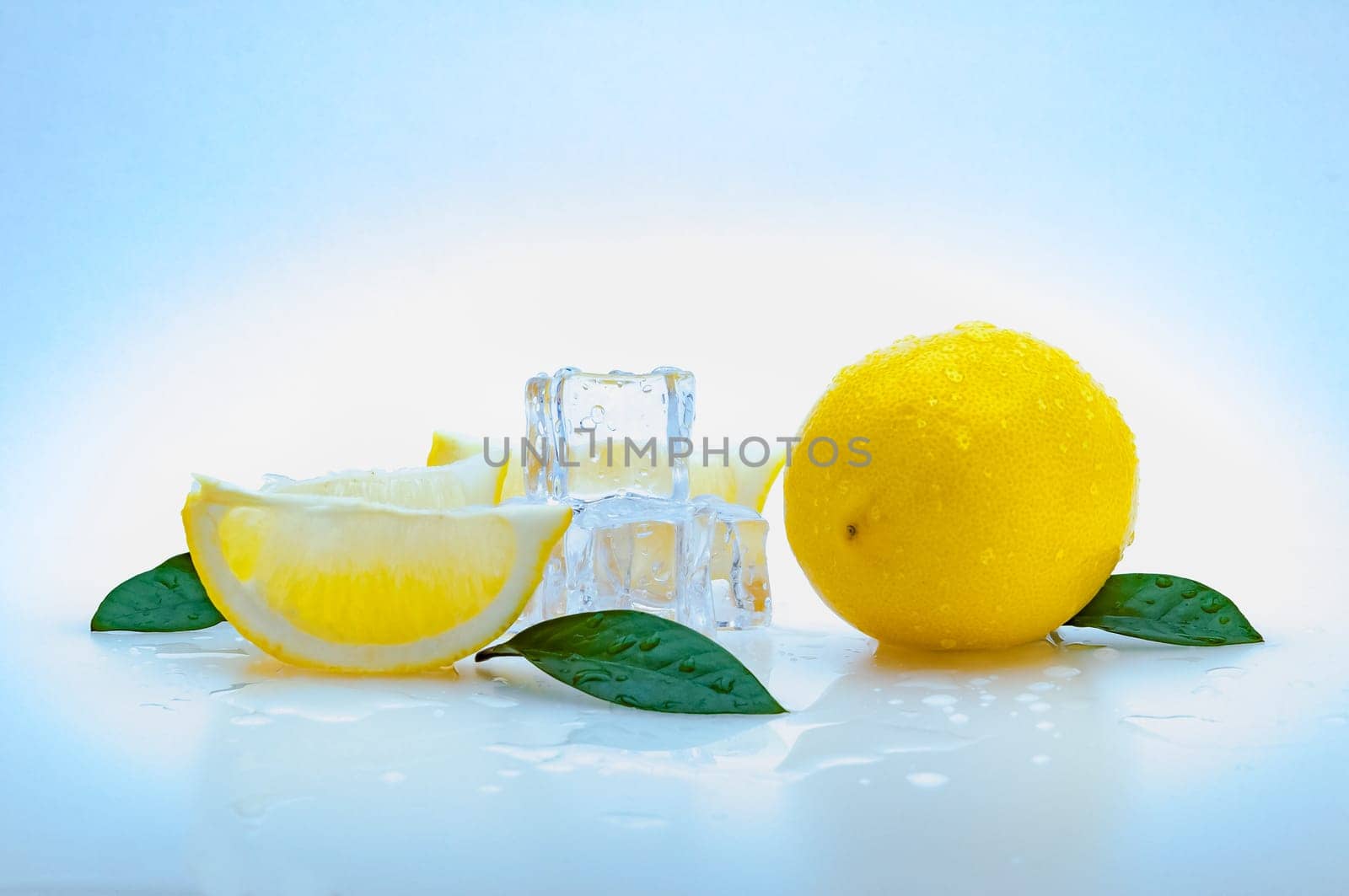 a whole fresh yellow lemon, slices of lemon, green leaves, cubes of ice, and on a blue background. isolated.