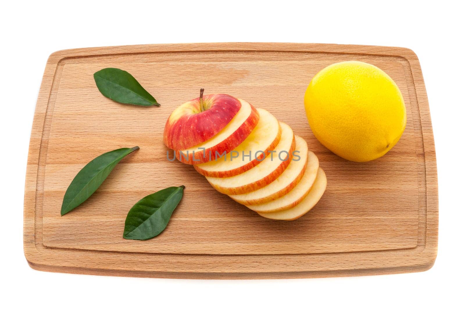 apple fresh and juicy with green leaves and lemon on a cutting board made of wood.