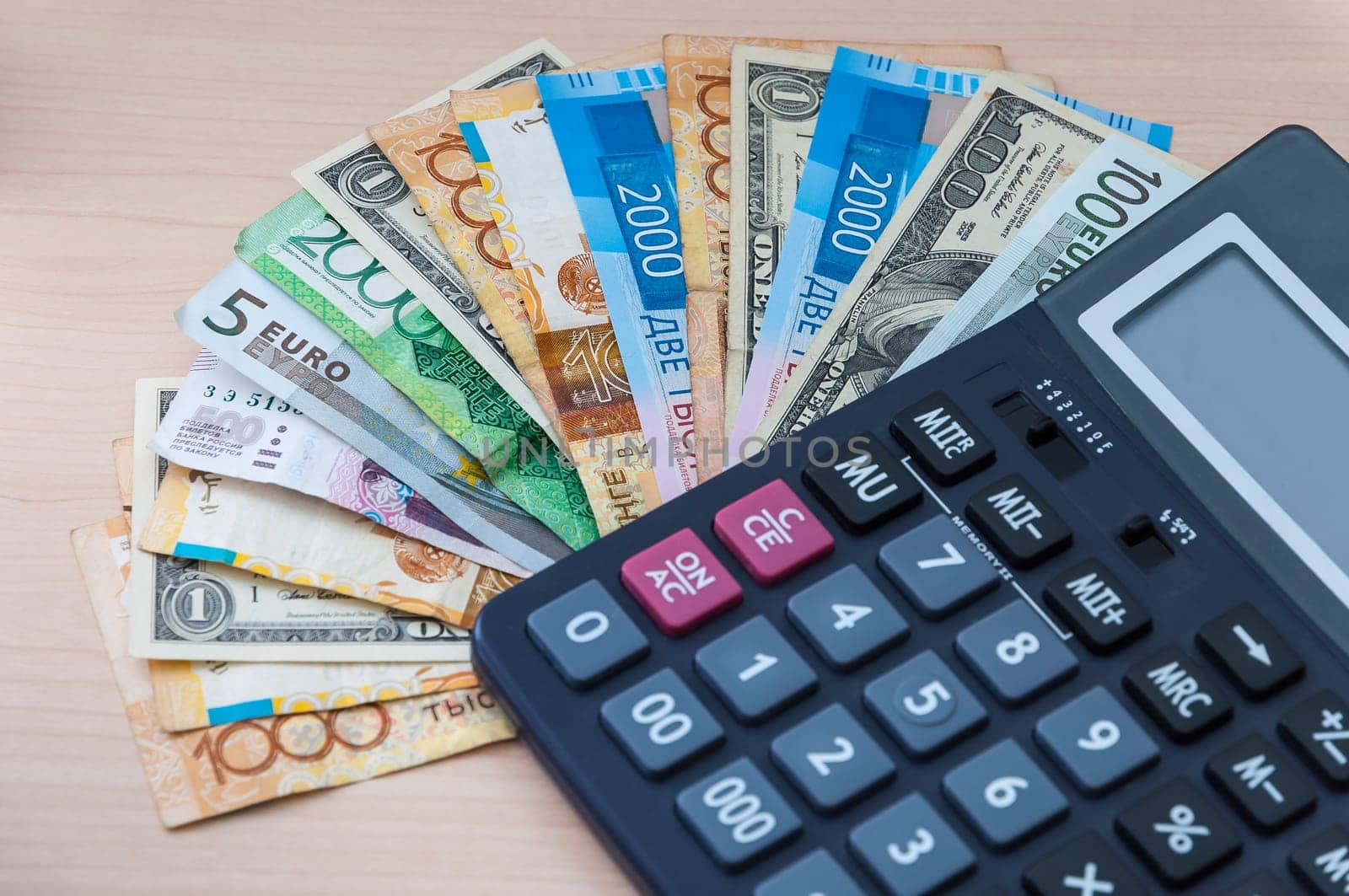 Different banknotes of different denominations are stacked in a fan and a calculator.