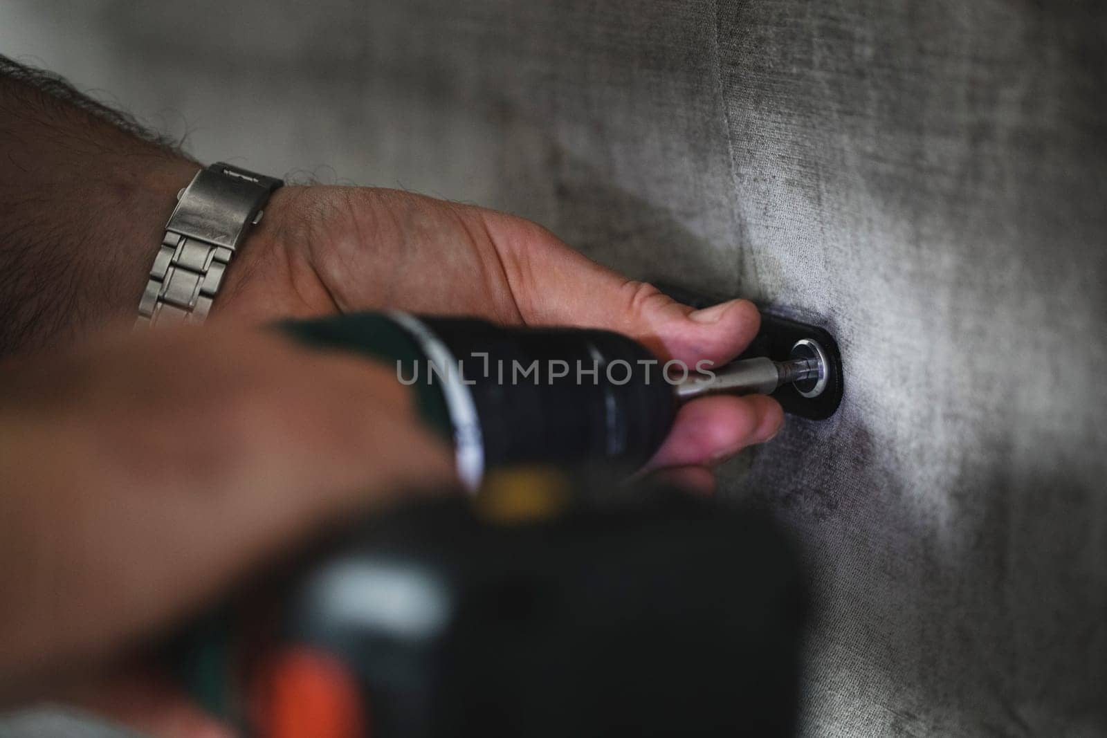 Close up shot of a man using a light-assisted power drill to put together some furniture.