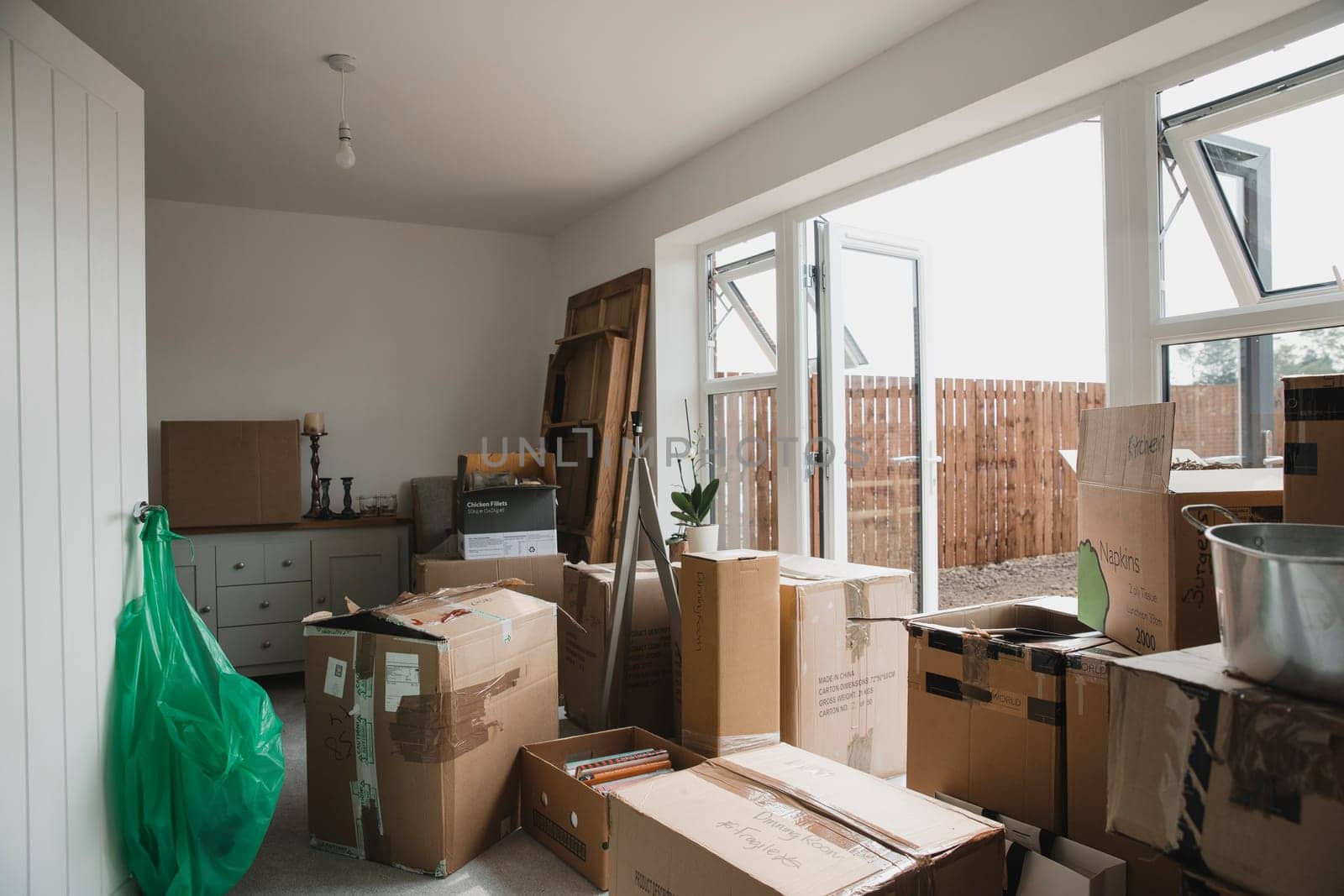 Dining room is full of furniture and cardboard boxes as a family are moving in.