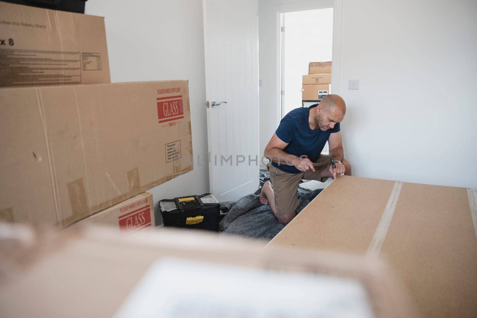 Mature man is putting a wardrobe together in a bedroom of a new home.