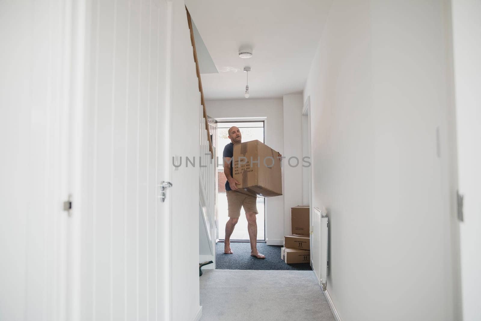 Mature man is carrying boxes in to his new home.