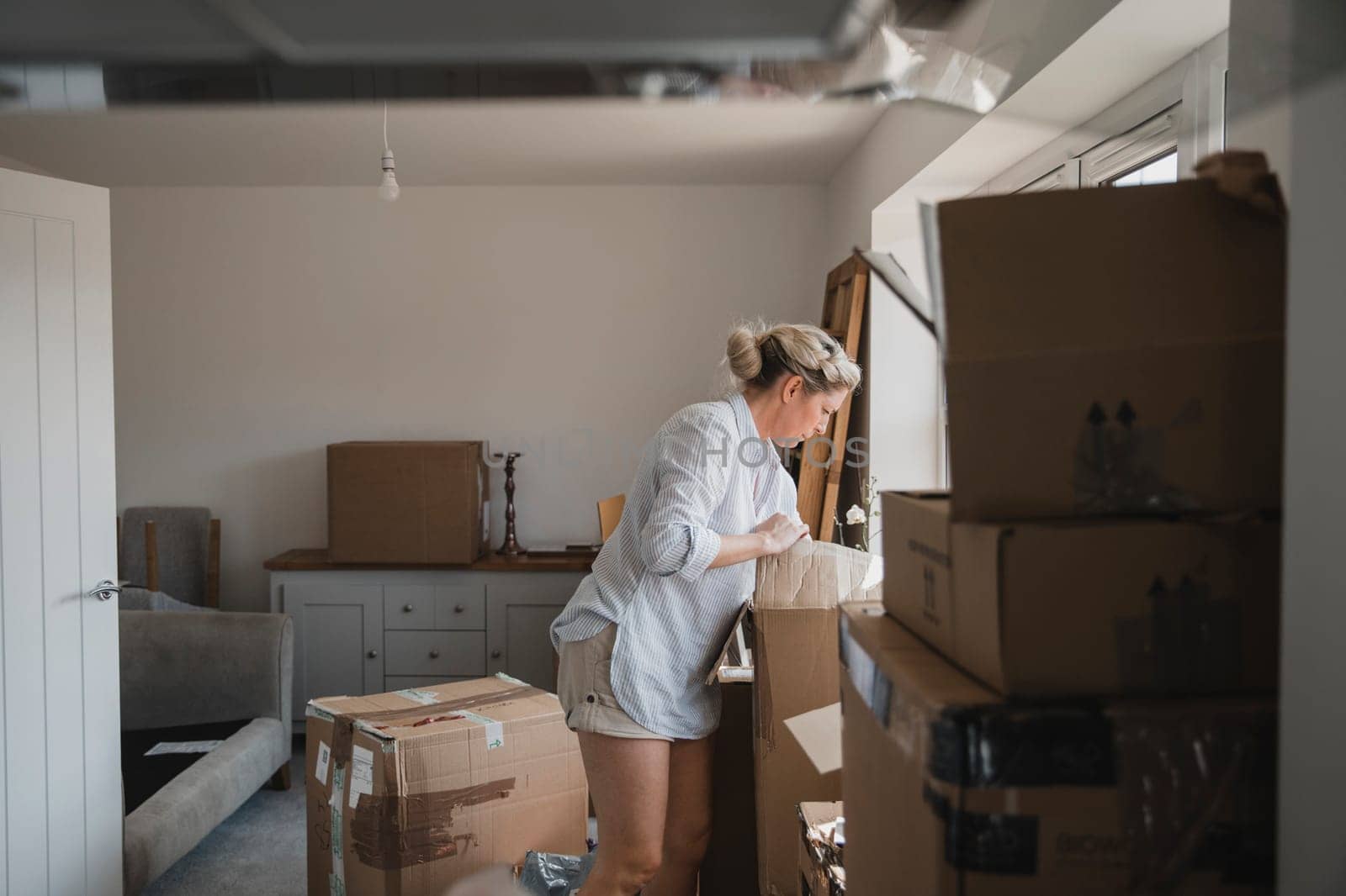 Mature woman is unpacking boxes in her new home.