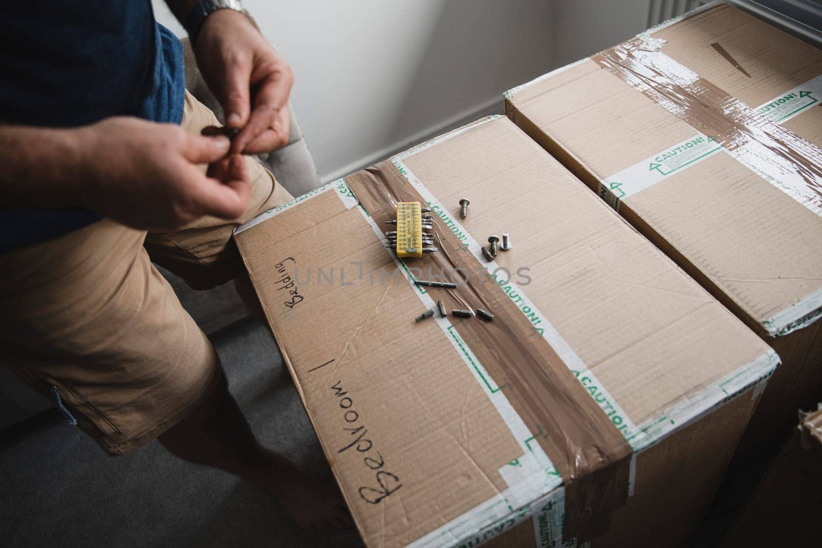 Close up shot of a mature man choosing drill bits while putting furniture together in his new home.
