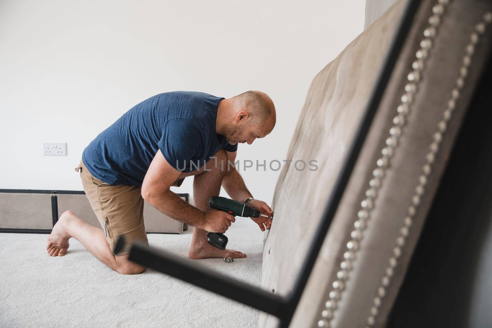 Mature man is building a bed in his new home.