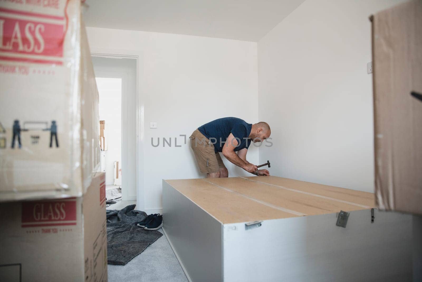 Mature man is putting a wardrobe together in a bedroom of a new home.