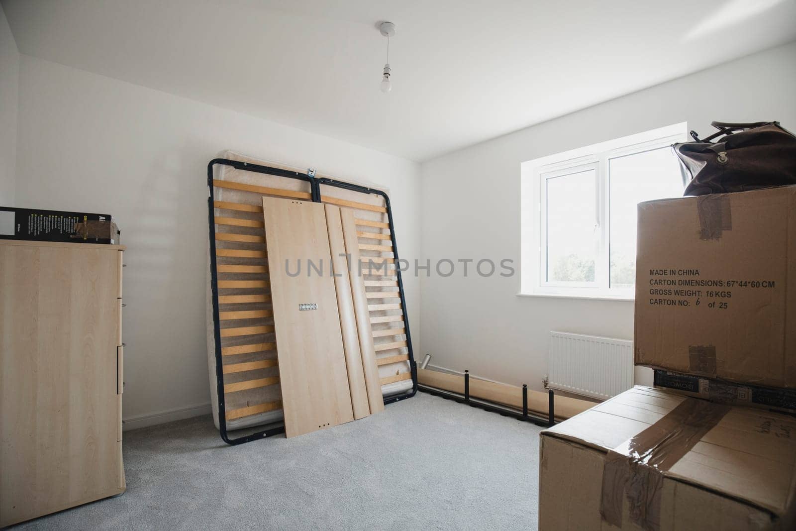 Bedroom of a new home with flatpack furniture and cardboard boxes.