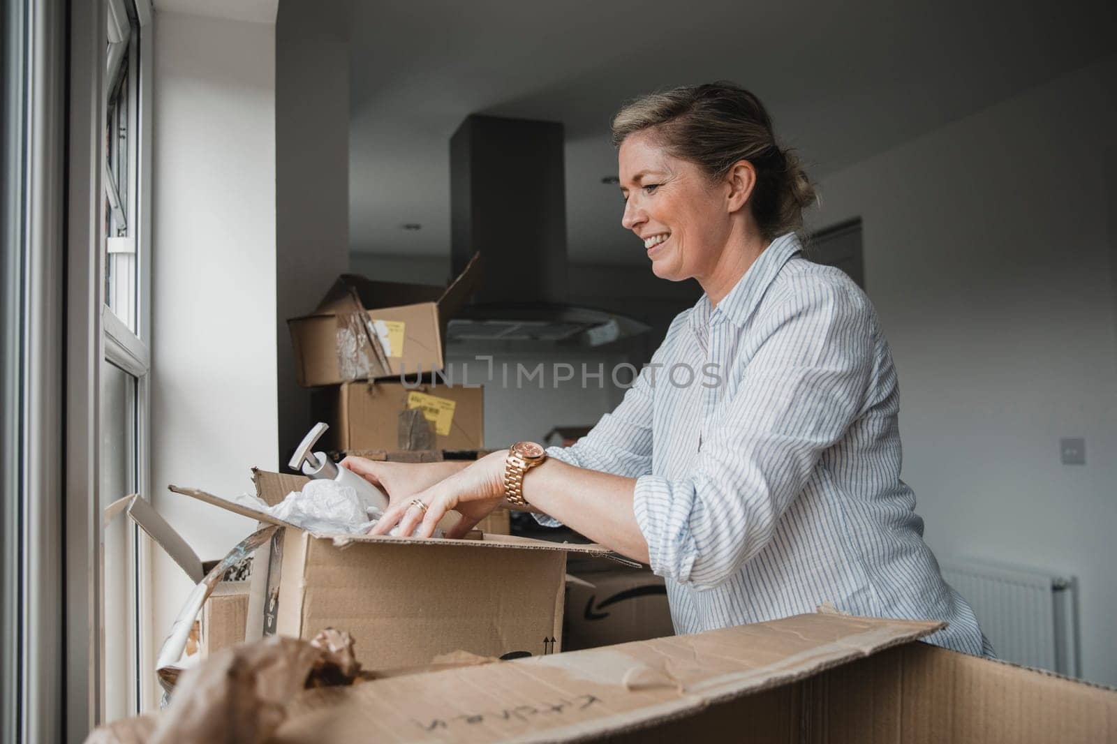 Mature woman is unpacking boxes in her new home.