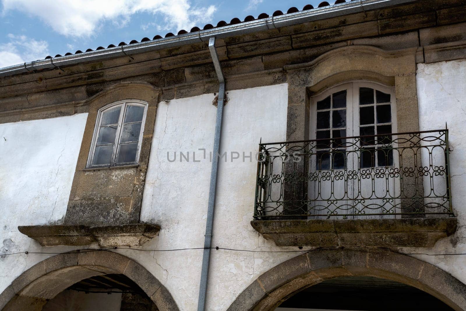 Arcade and classic windows in local granite stone on an old building on main street of historic town of Trancoso, Portugal