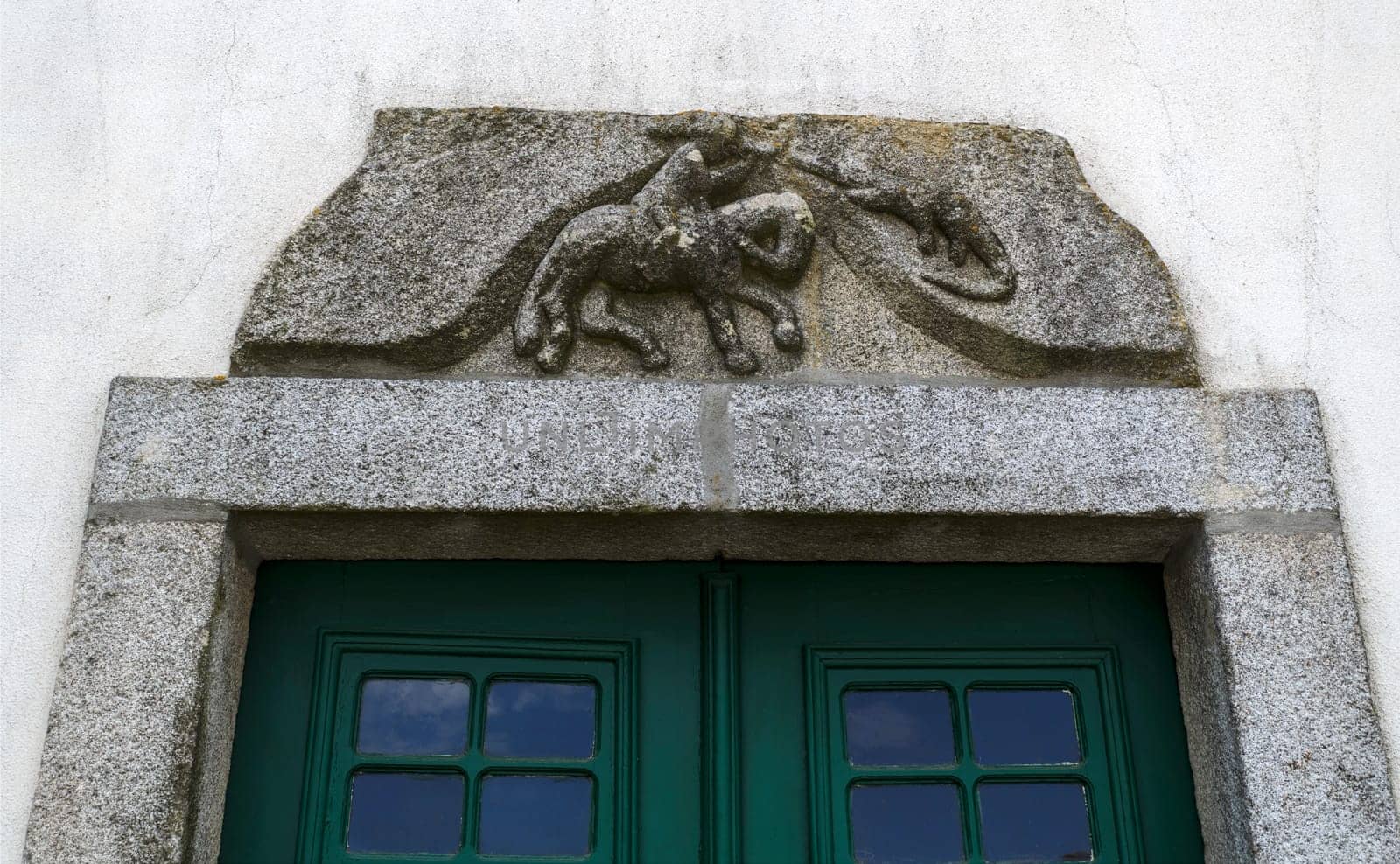 Granite stone with a bas-relief sculpture of St George Killing the Dragon on top of a door in the historic centre of Trancoso, Portugal