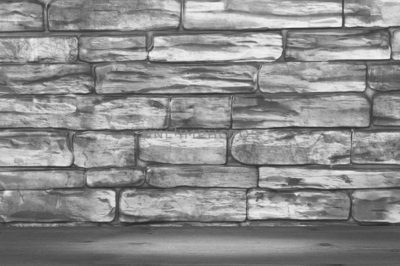 The wall is made of bricks of black and white color and wooden boards with a spot of illumination.