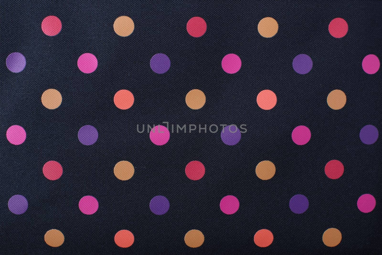 Close-up seamless texture background of colorful polka dots pattern on a black textile background.