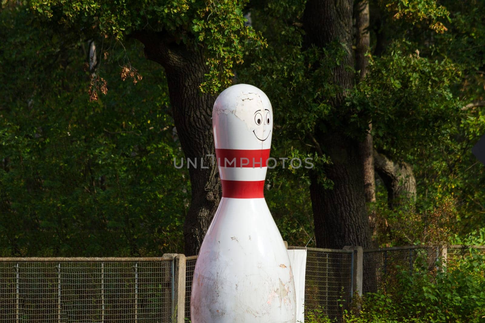 Bowling cone with white and red stripes in front of green background