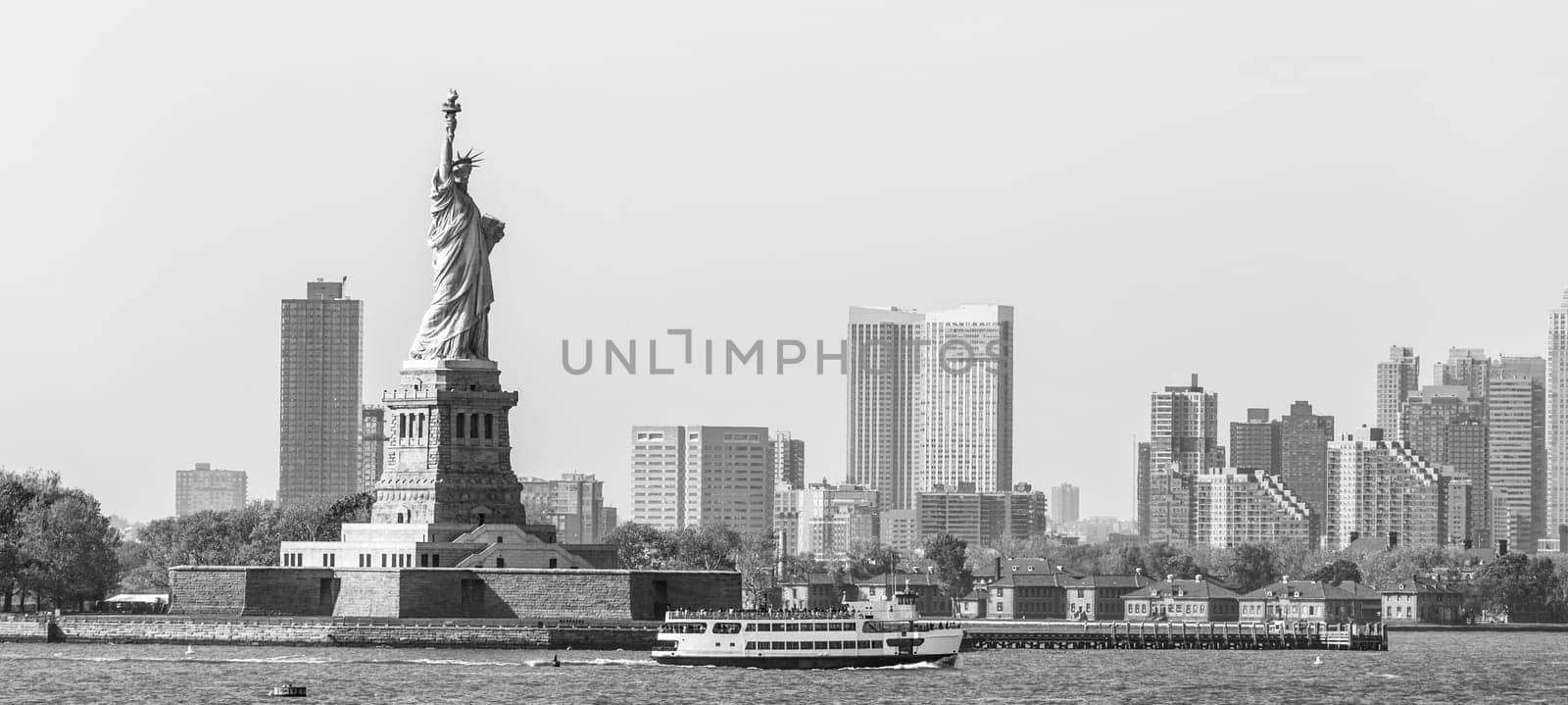 Statue of Liberty with Liberty State Park and Jersey City skyscrapers in background, USA. Black and white image.