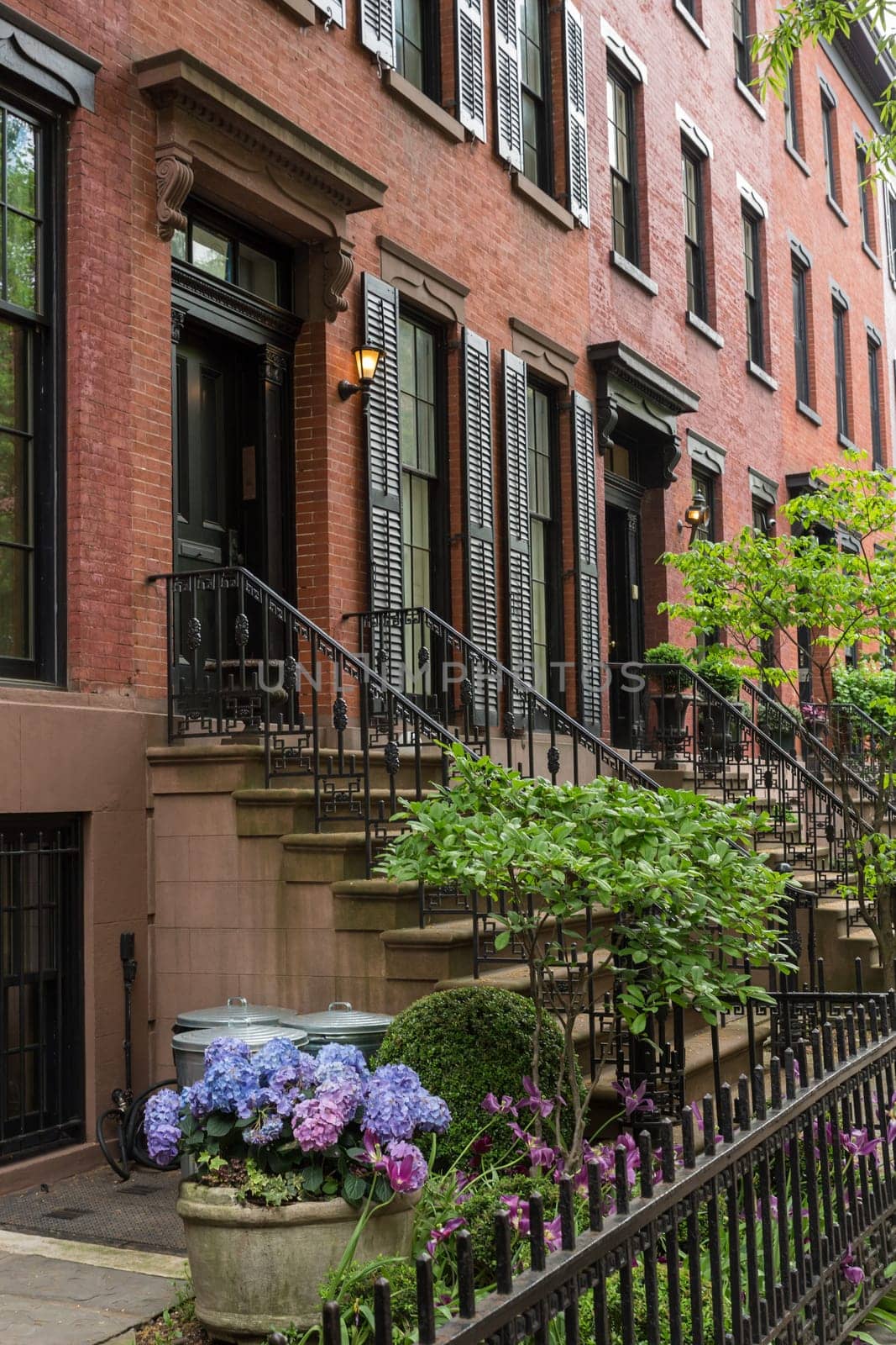 Row of old brownstone buildings along an empty sidewalk block in the Greenwich Village neighborhood of Manhattan, New York City, NYC, USA.