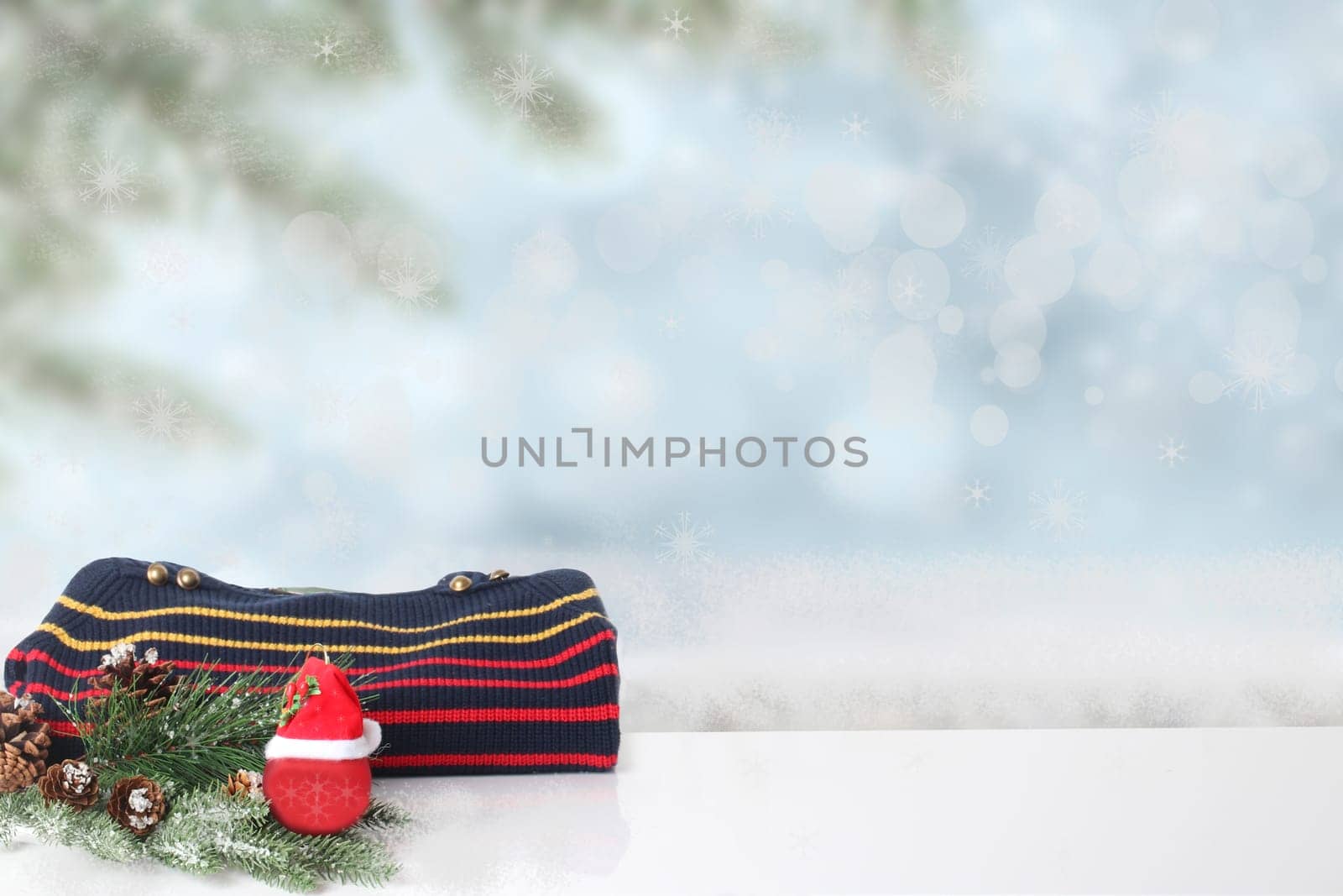 Autumn and winter children clothes. A red black striped cozy warm sweater or pullover with Christmas decorations over abstract winter landscape. Space for your design.
