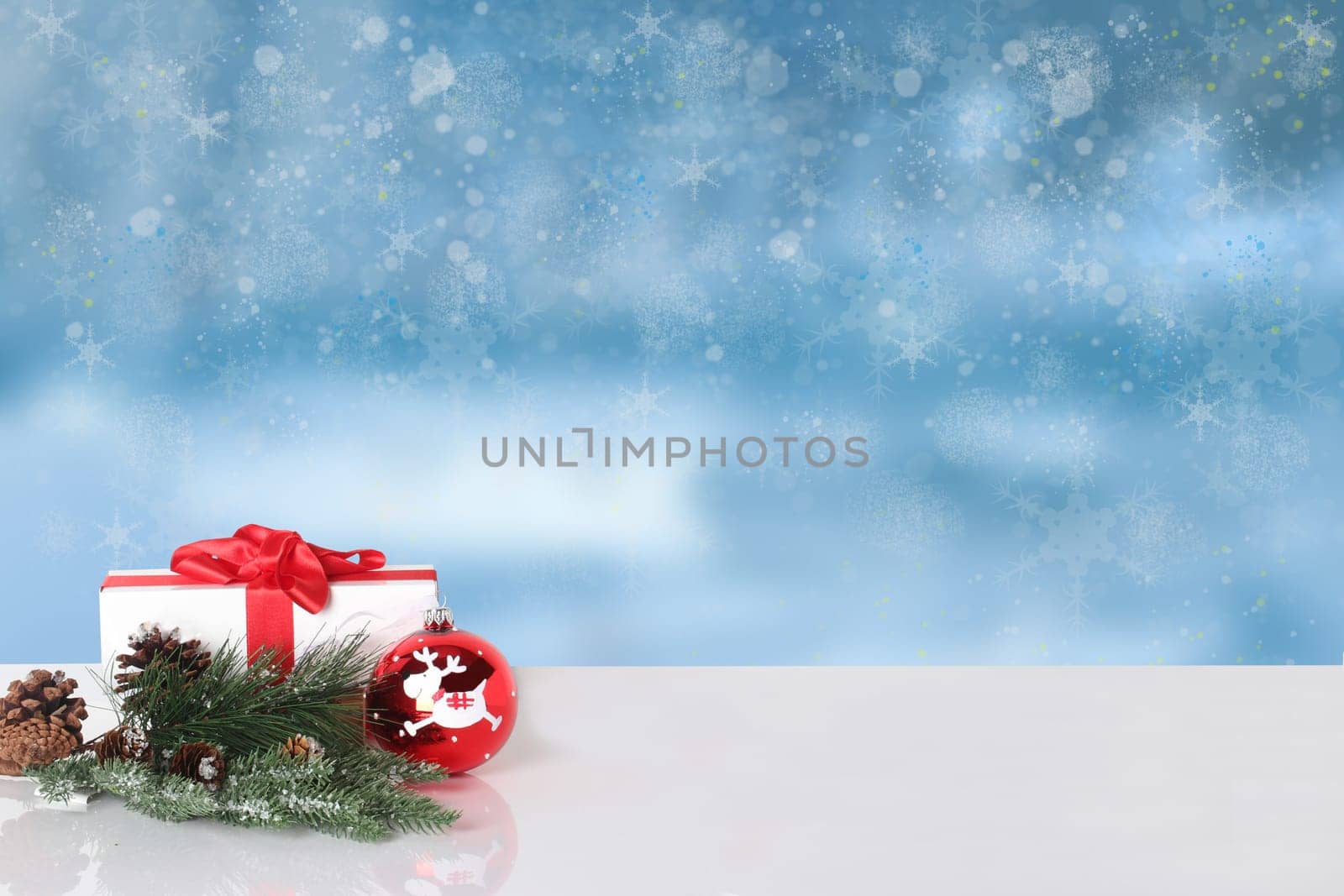 Christmas greeting card.  Christmas gift and Christmas decoration on white table over abstract winter landscape. Template for your product display montage.