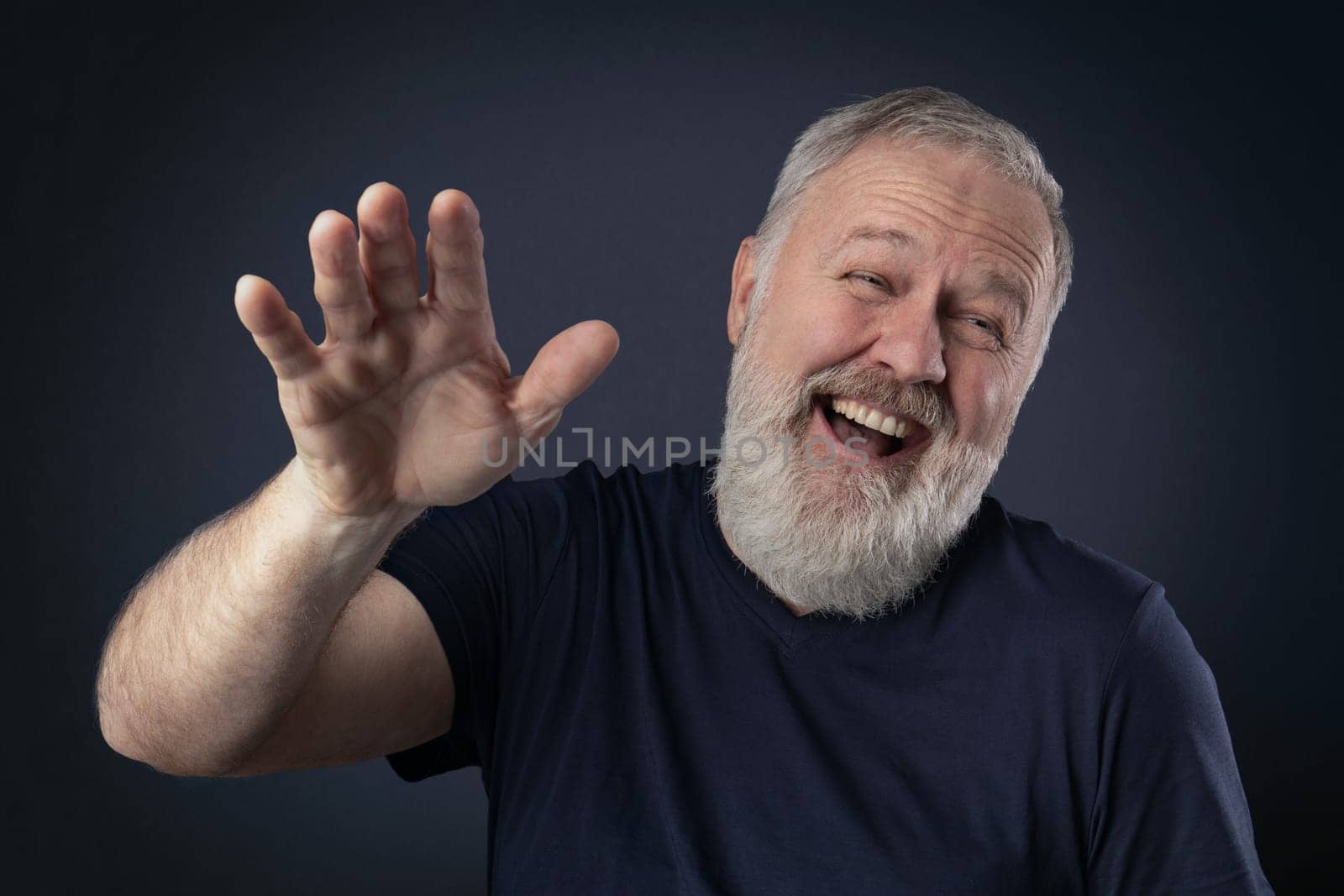 Elderly man with gray beard laughing with his palm up