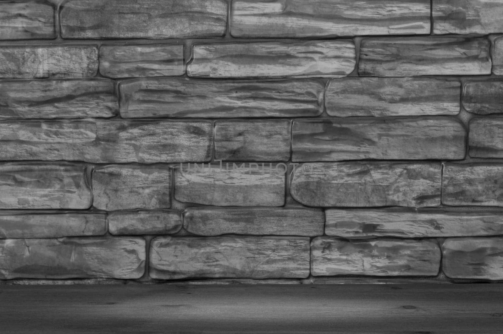 The wall is made of large bricks of black and white color and wooden boards with a spot of illumination.