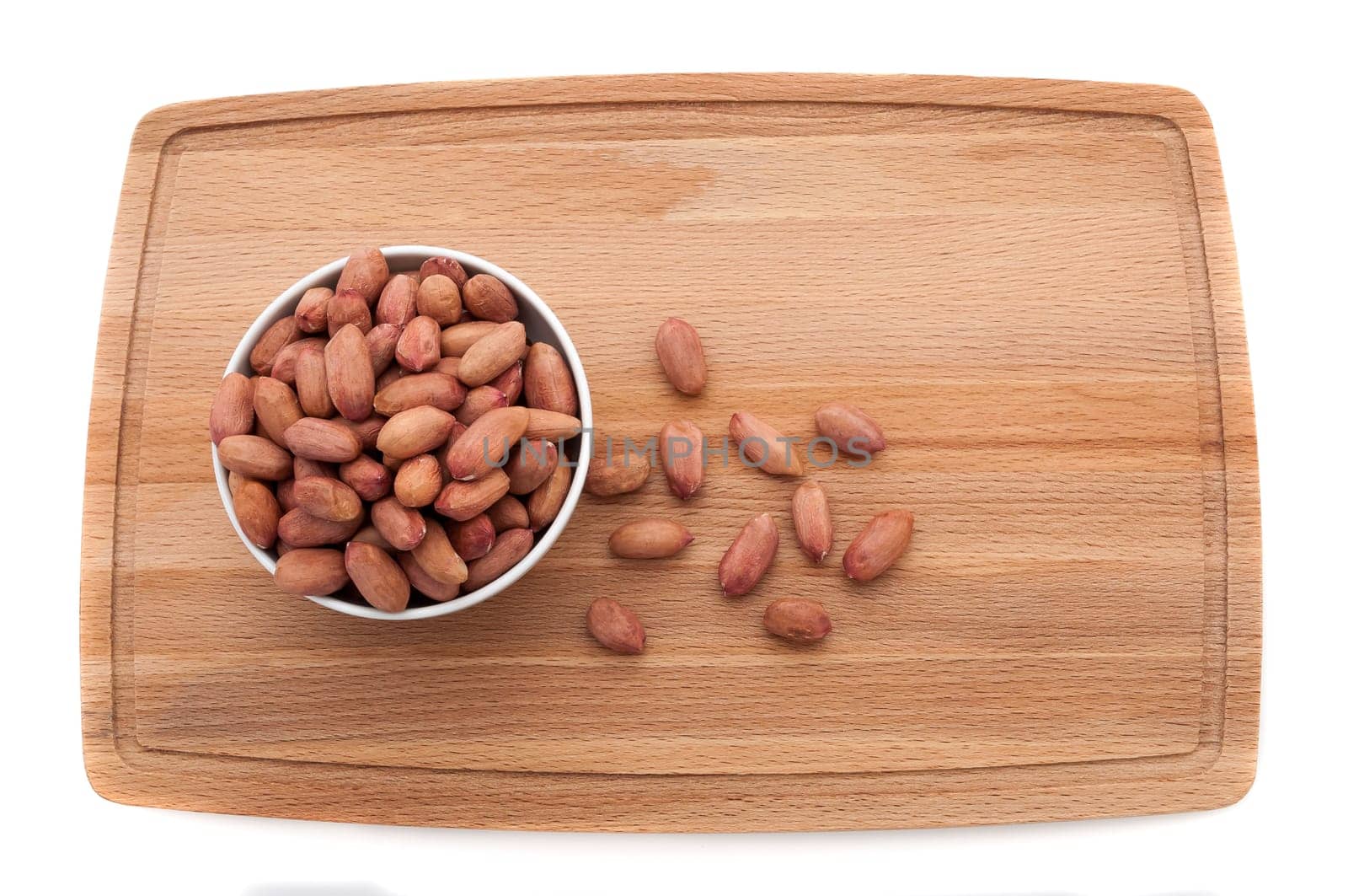 Peanut grains in a cup on a cutting board.
