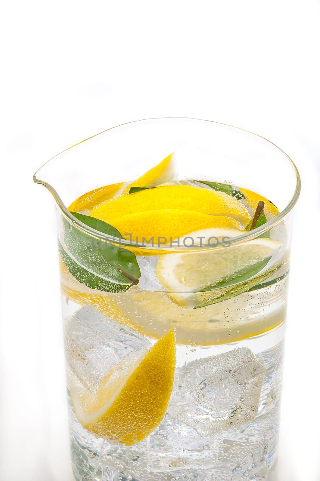 A full jug of drink from ice, lobules of fresh juicy yellow lemon and crystal clear water.