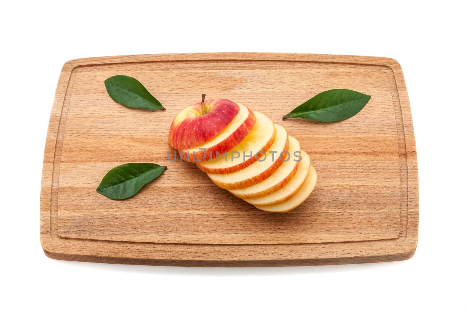 Sliced delicious luscious apple with leaves on a cutting board made of wood.