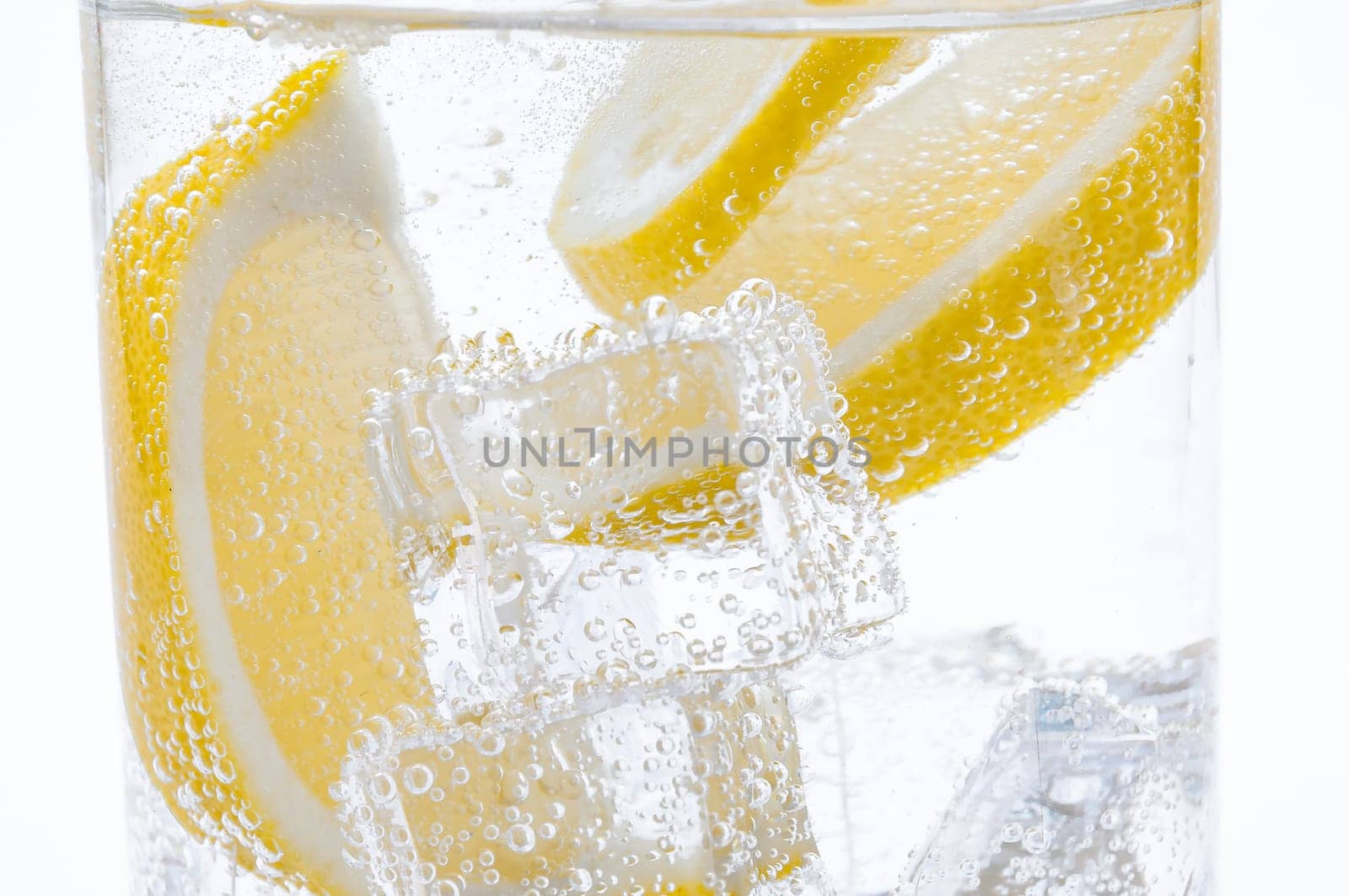Slices of fresh juicy lemon drop into the cocktail with crystal clear water.