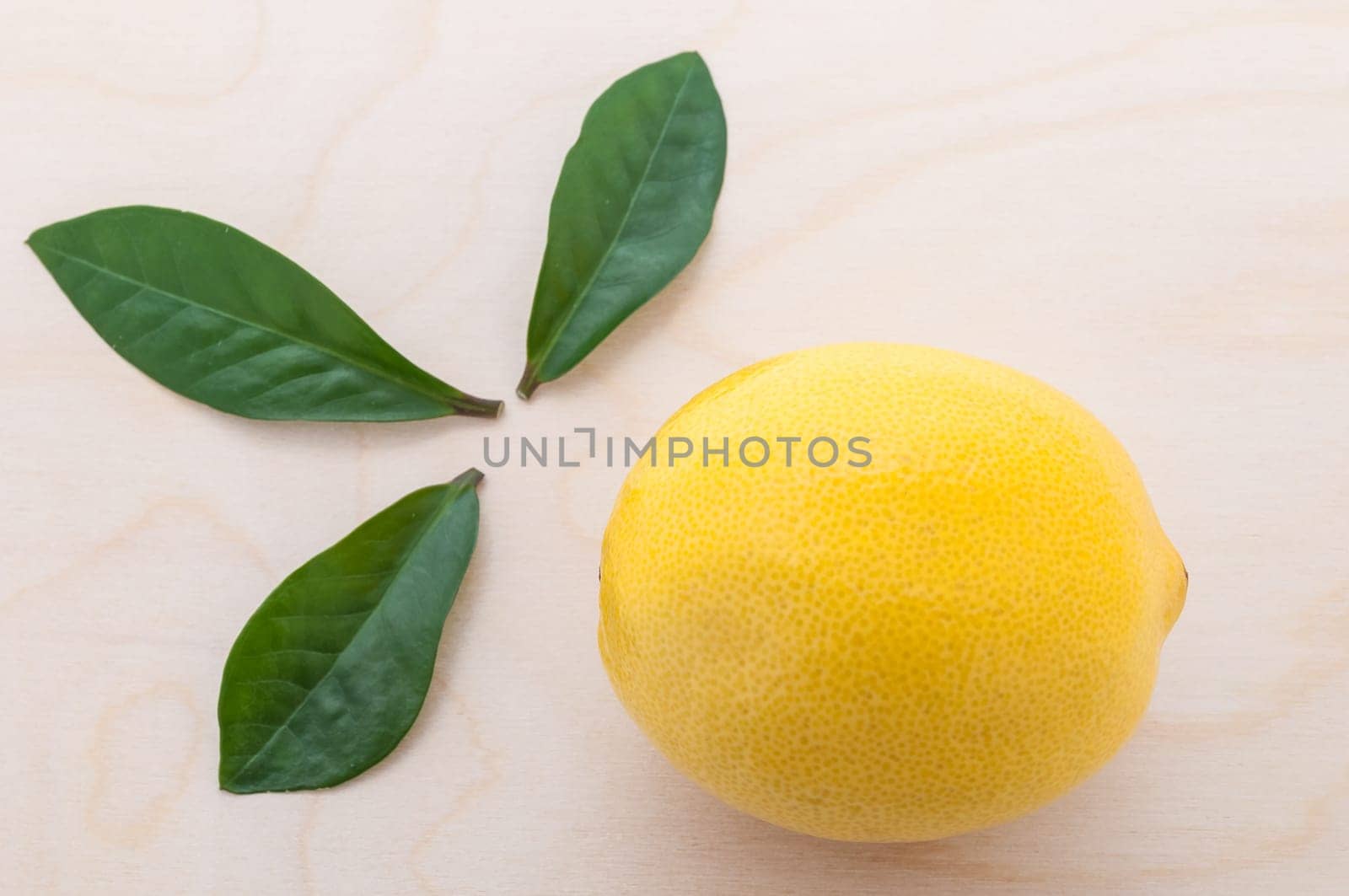 yellow bright lemon with three green leaves close-up on a cutting board