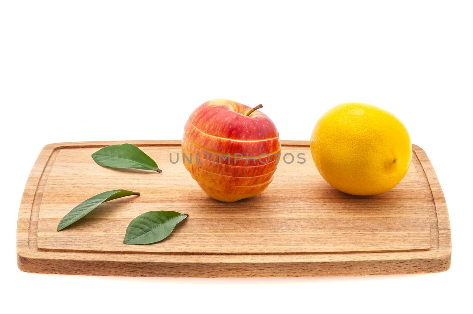 apple tasty, fresh and juicy with green leaves and lemon on a cutting board made of wood.