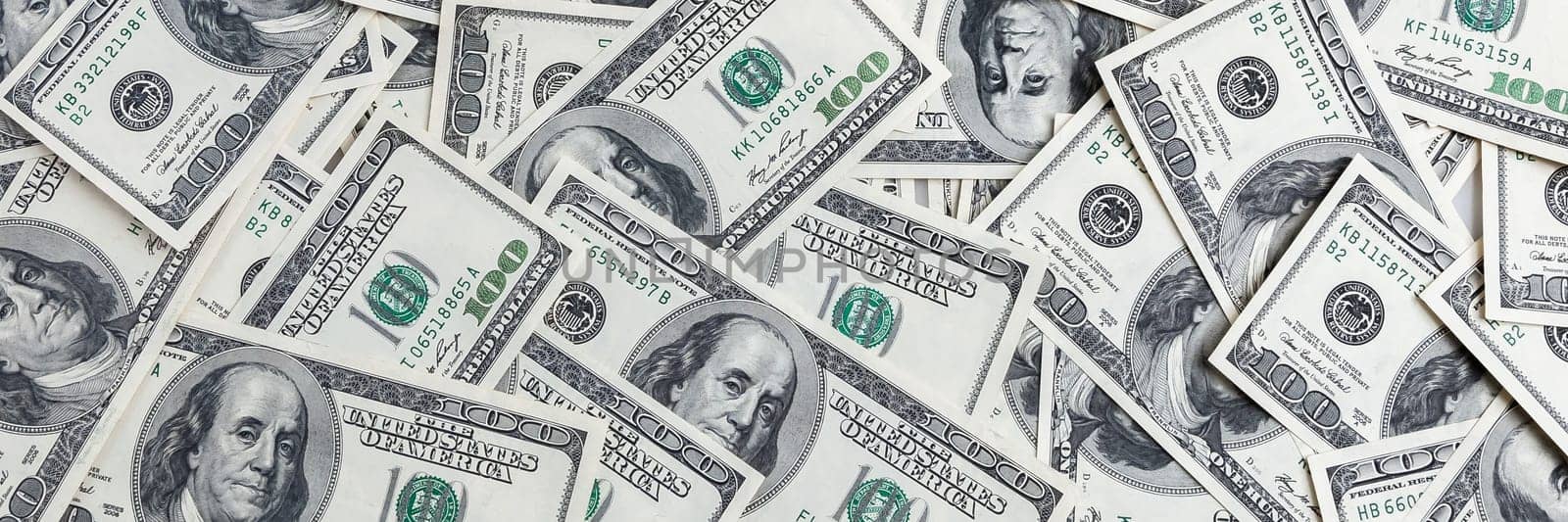 A pile of one hundred US banknotes with president portraits. Cash of hundred dollar bills, dollar background image.