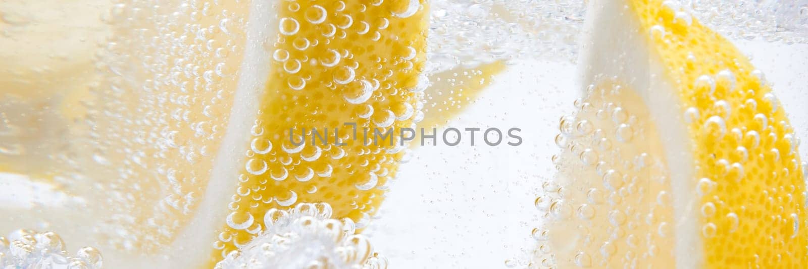 In a glass with cubes of melting ice slices of a juicy yellow lemon.