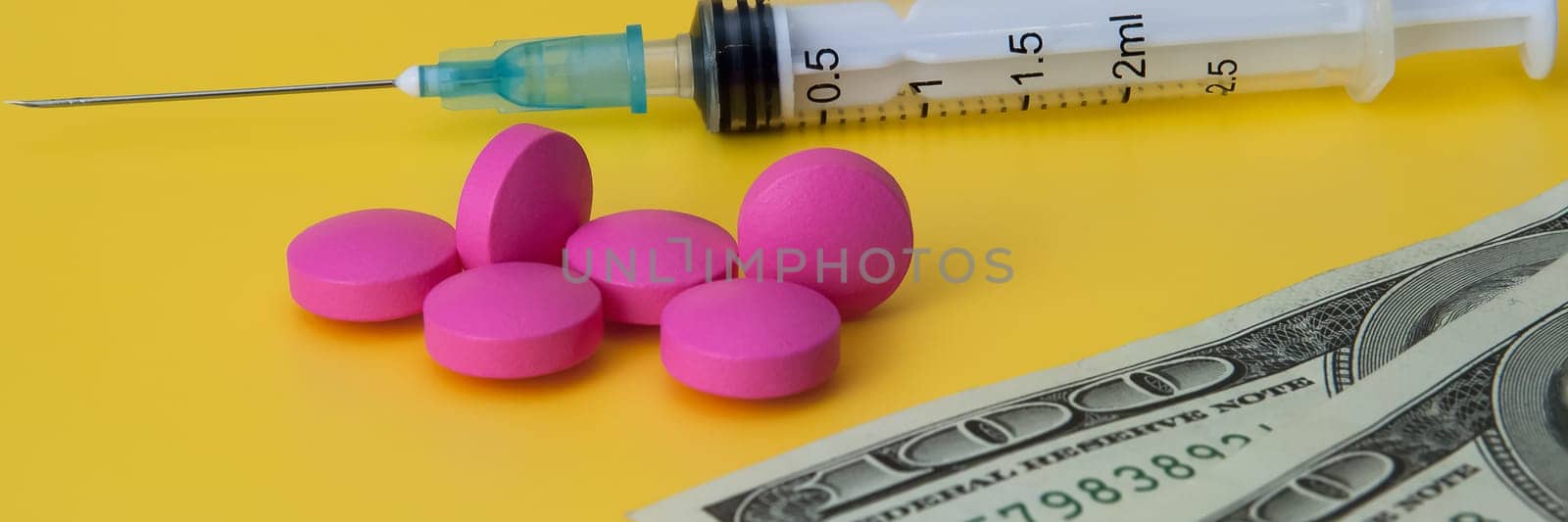 Syringe, several pink pills and dollars on a yellow background.