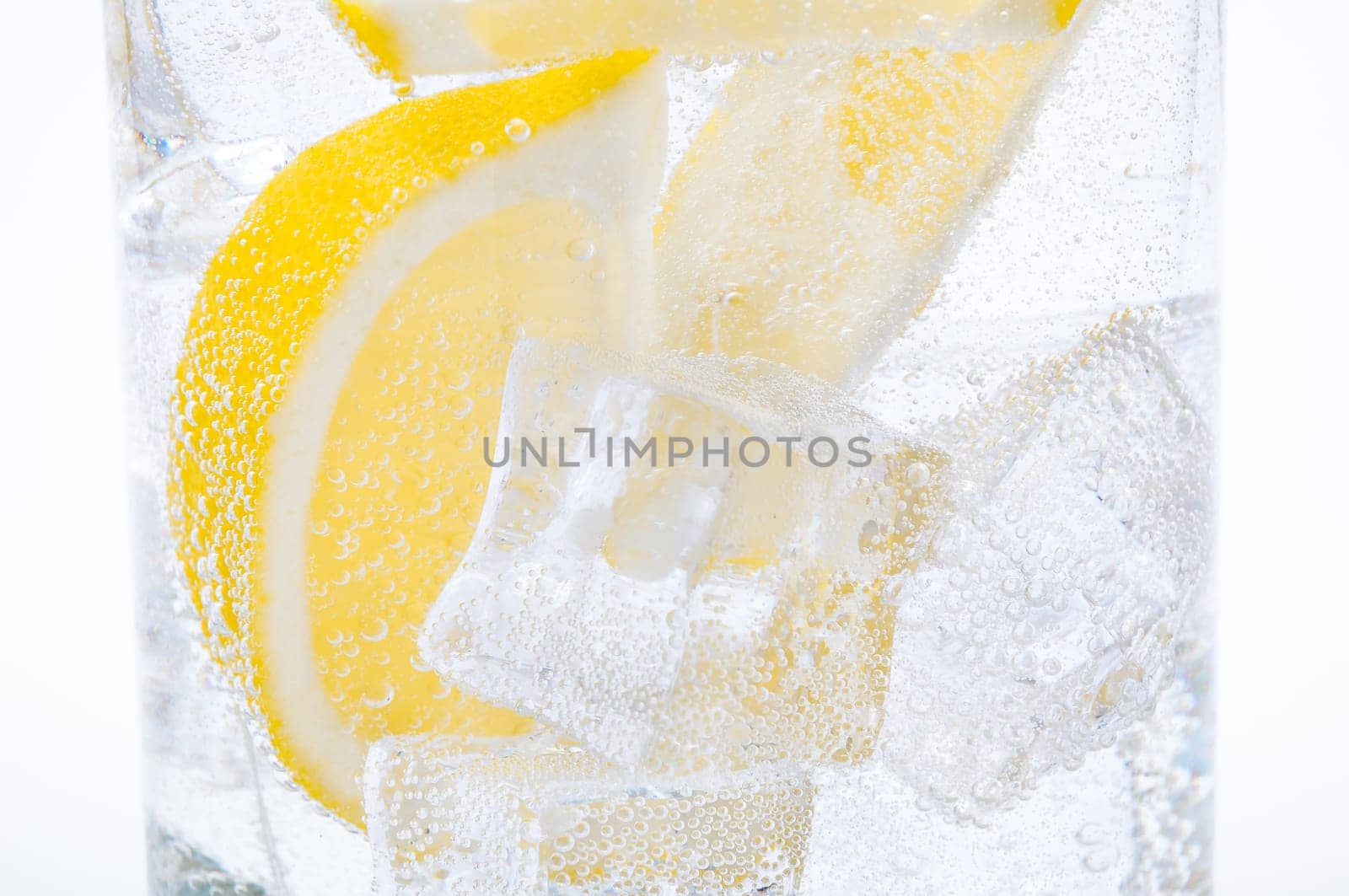 Ice, lemon slices and crystal clear water in a glass.
