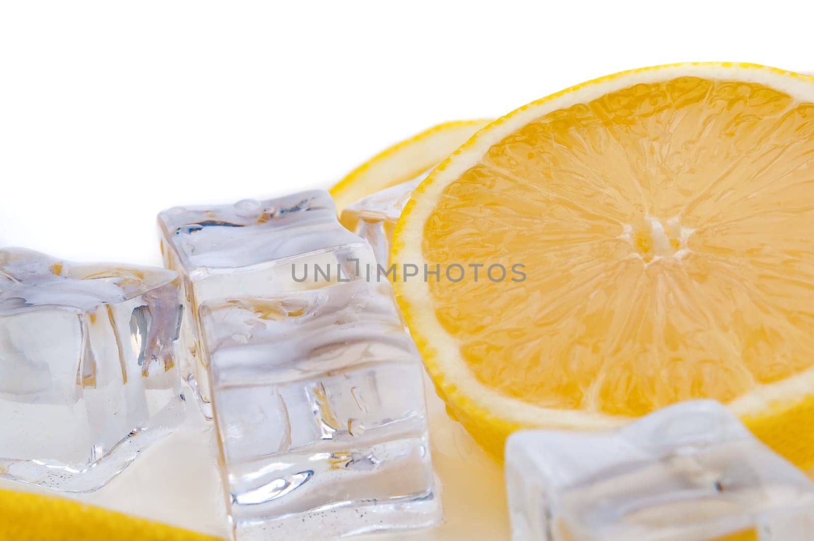 Half of juicy bright lemon and cubes of refreshing ice close-up on white background