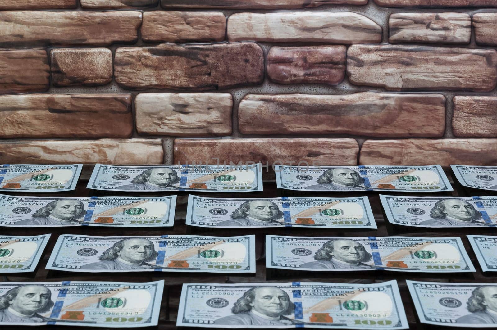 bills of one hundred dollars on a table of black glass near a brick wall