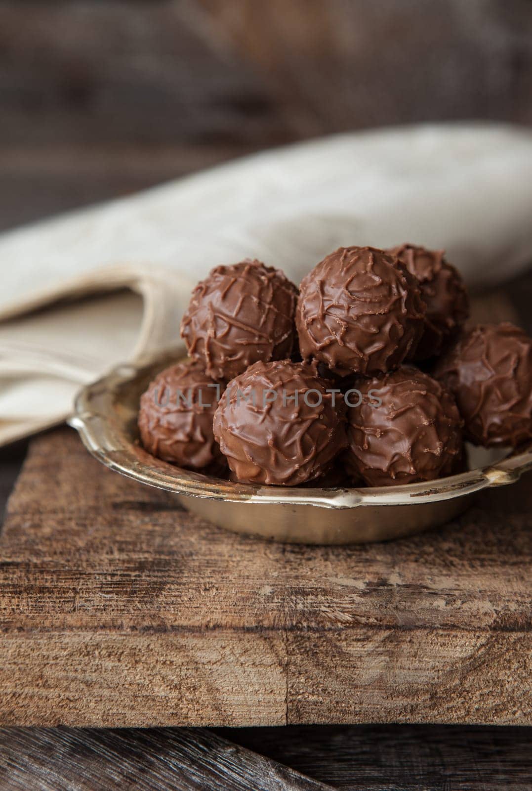 Little plate with truffle chocolates in front of a dark wooden background