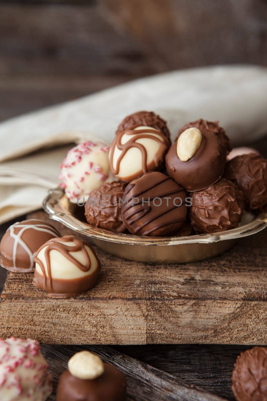 Little plate with truffles and chocolates in front of a dark wooden background