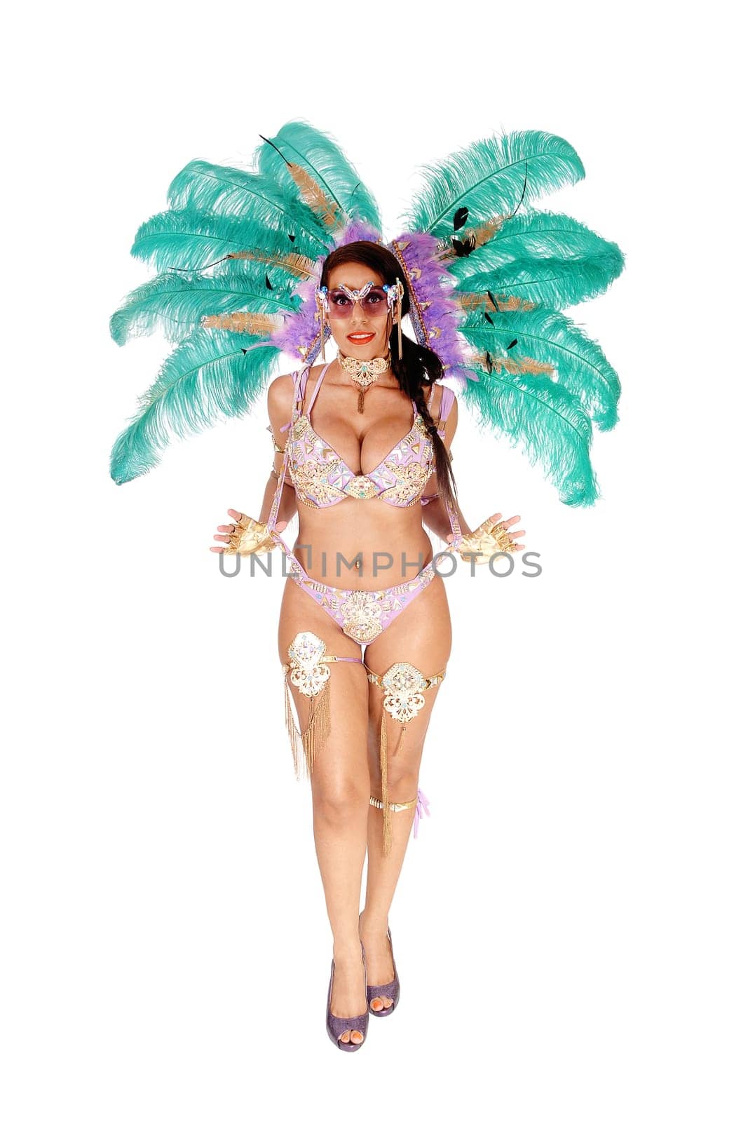 A young gorgeous woman wearing a colorful carnival outfit with big.feather, high heels and jewellery, isolated for white background.