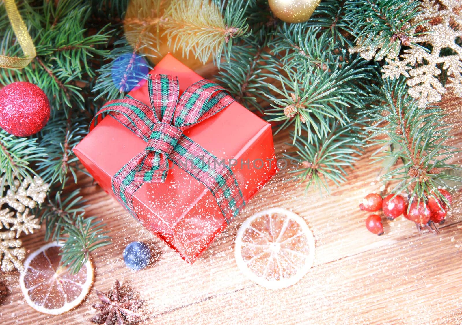 Christmas or winter decoration background. Christmas red gift box with sparkling christmas tree branches and xmas balls on a rustic wooden table. Closeup.