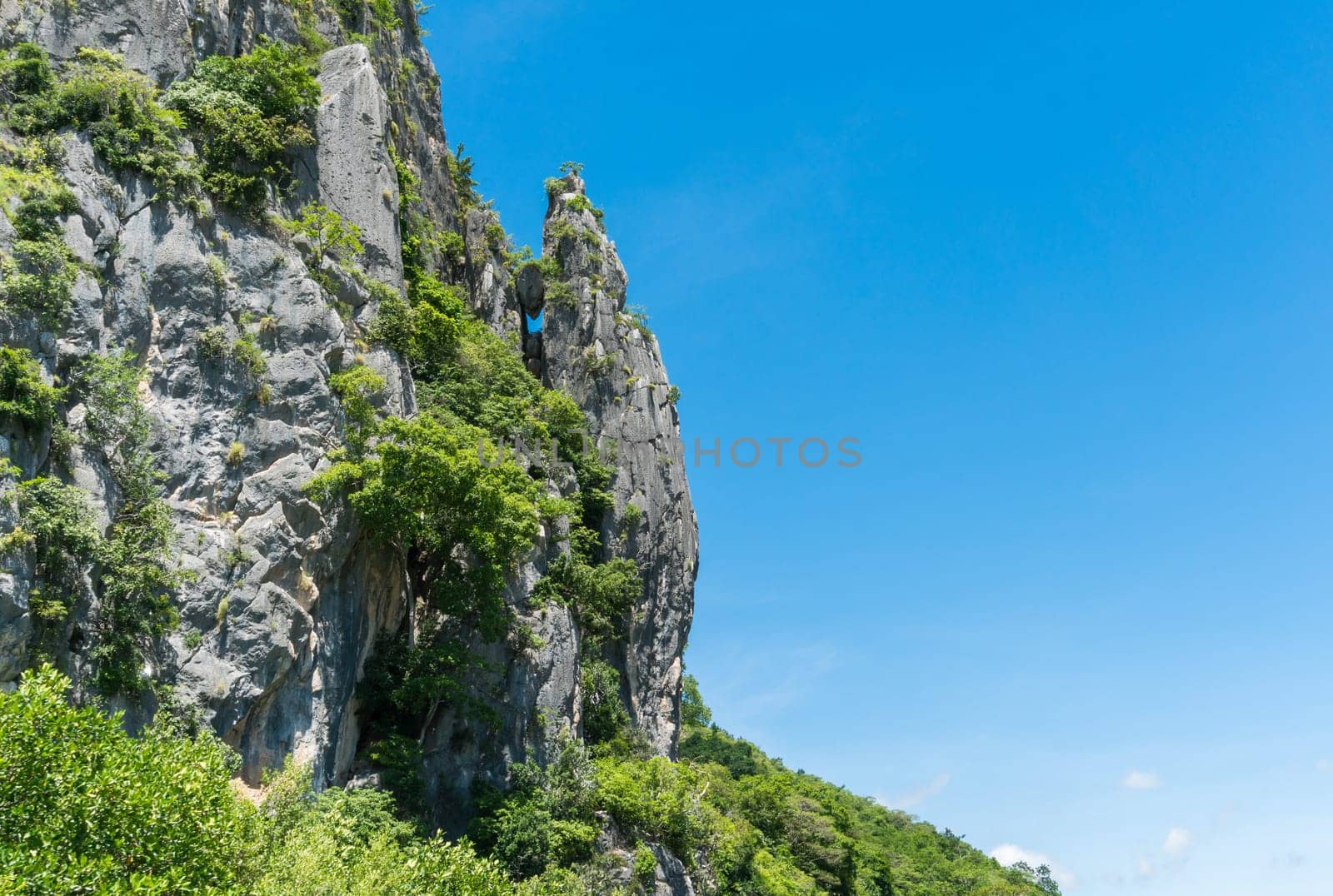 Stone or rock mountain or hill with green tree and blue sky and water and cloud at Khao Dang canal Prachuap Khiri Khan Thailand. Landscape or .scenery summer concept for boat trip