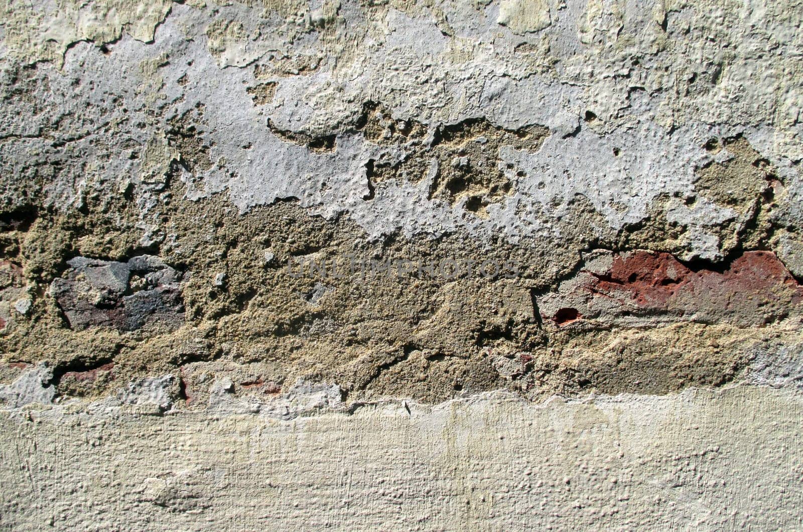 Stones under cracked plaster on the wall