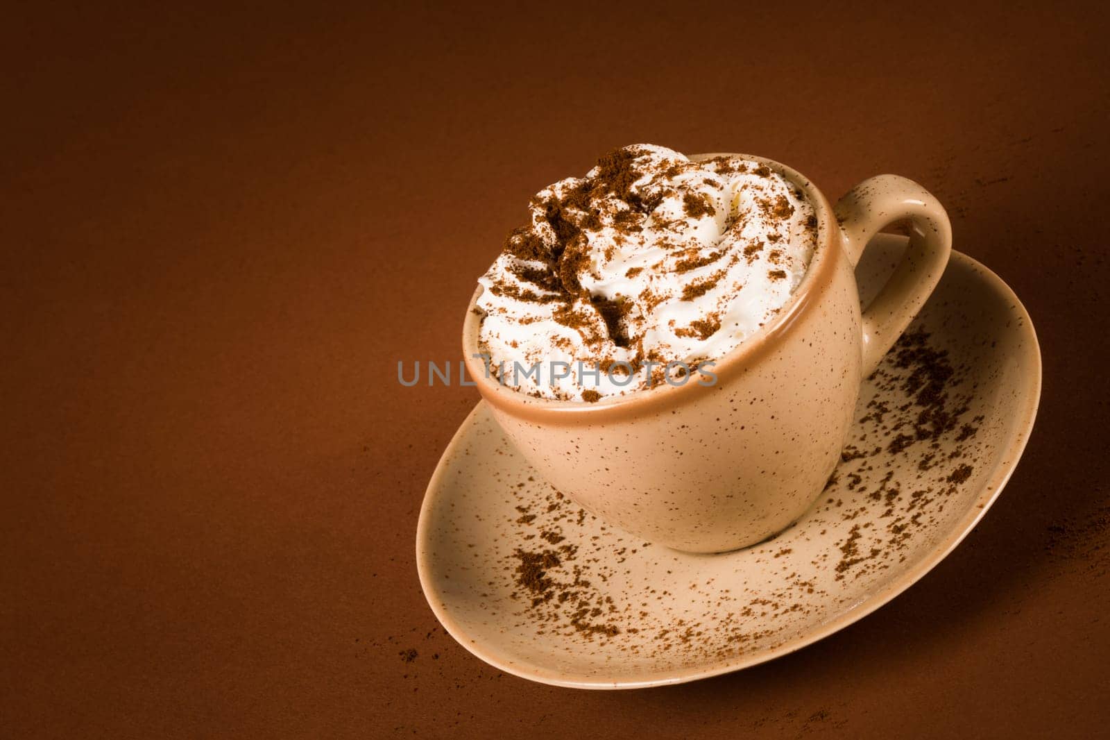 The coffee drink with whipped cream is on brown background.