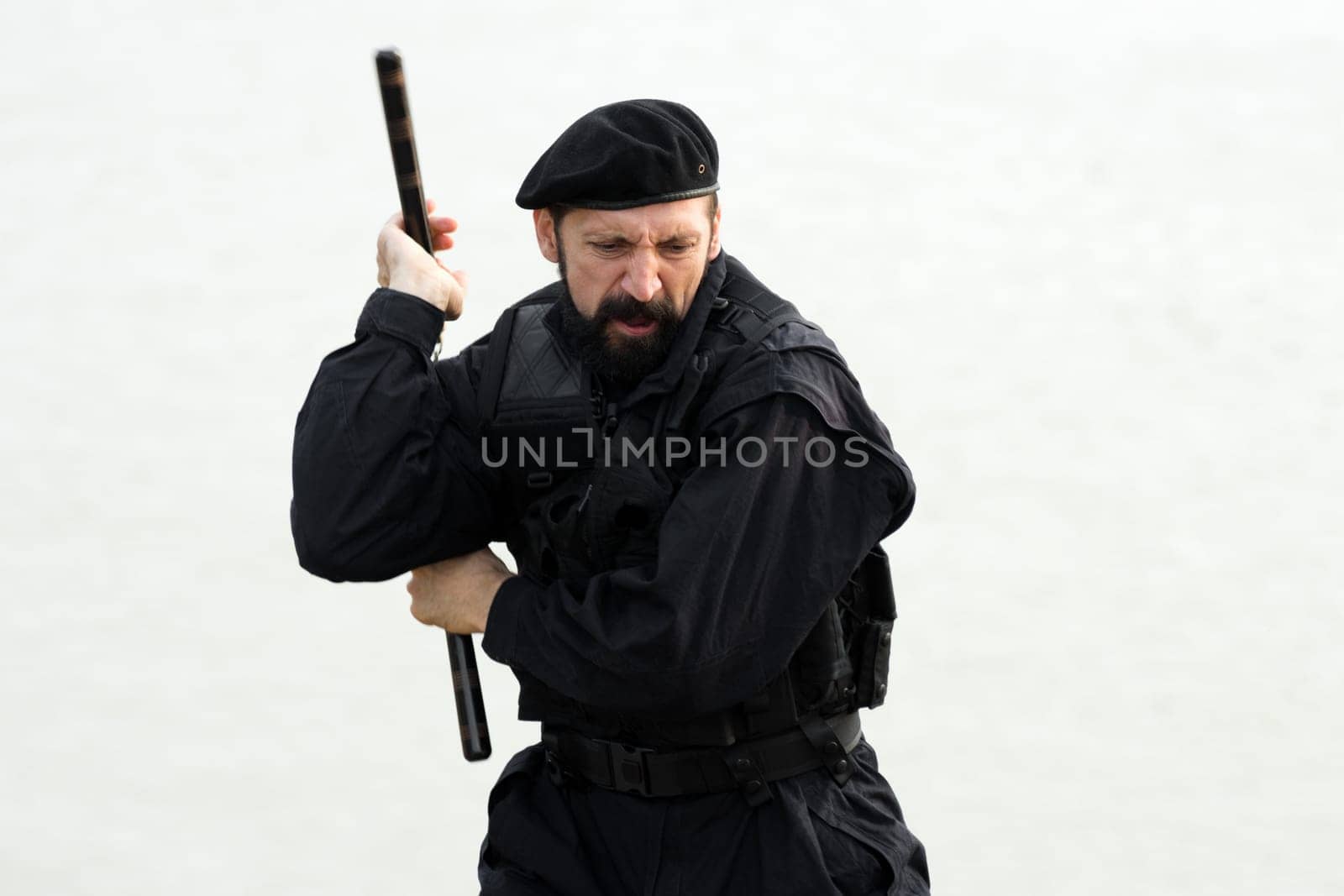 The security man in uniform and beret is practicing with nunchaku on white background.