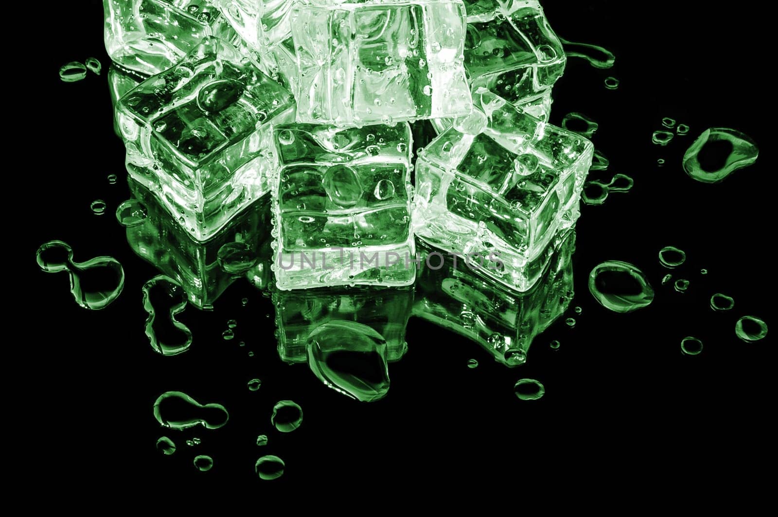 Hill of green ice cubes on a black glass with water drops.