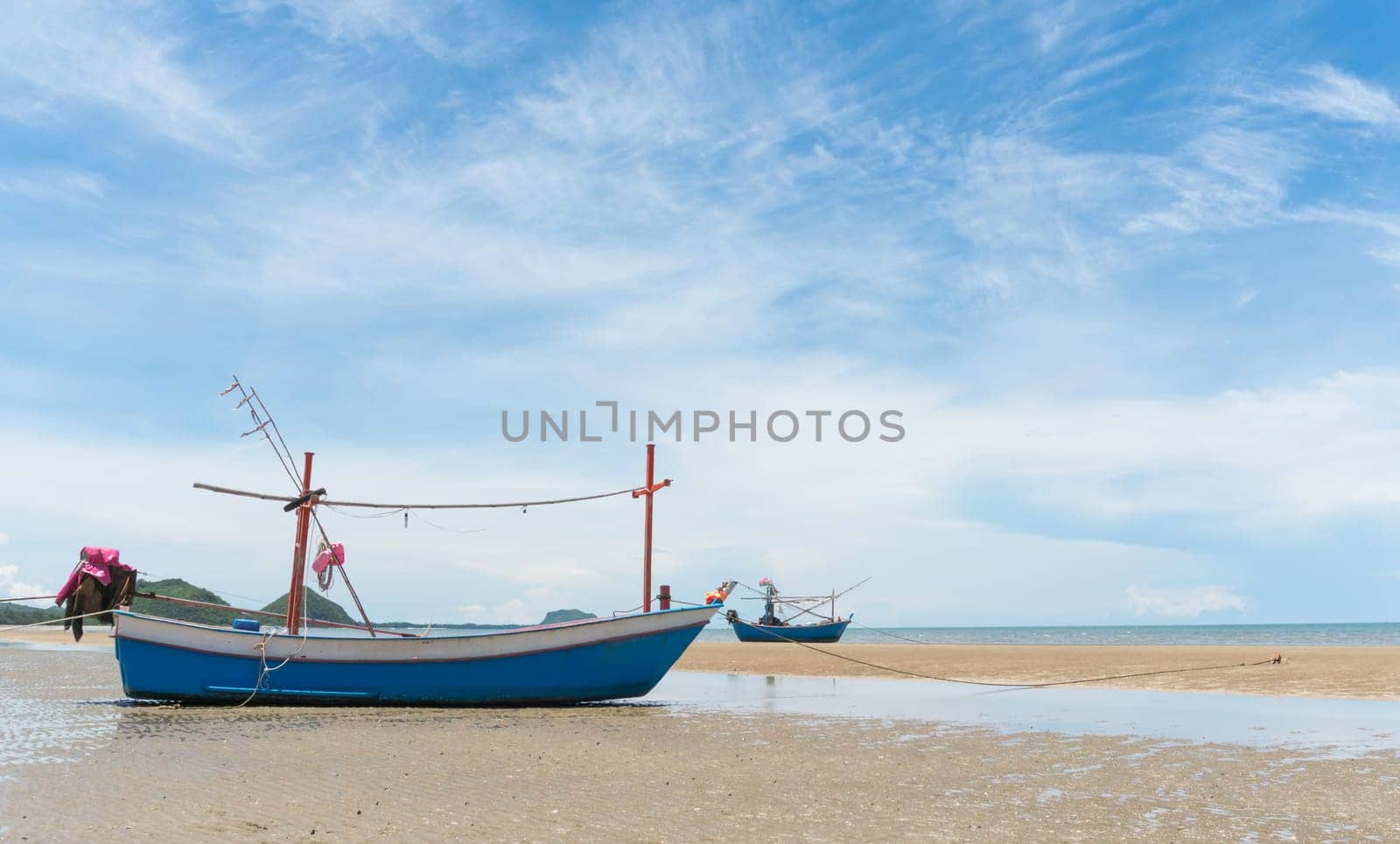 Blue fishing boat or fisherman boat or ship on Sam Roi Yod bech Prachuap Khiri Khan Thailand with blue sky and cloud and blue sea and .mountain or hill. Landscape or scenery for summer season concept