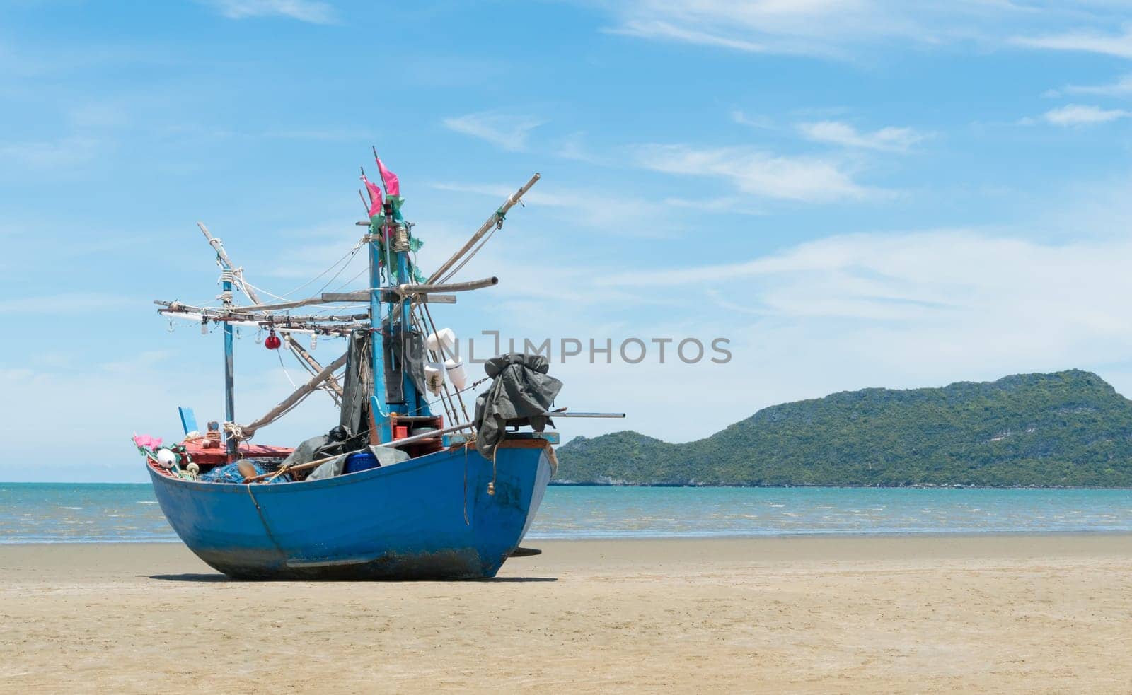 Blue fishing boat or fisherman boat or ship on Sam Roi Yod bech Prachuap Khiri Khan Thailand with blue sky and cloud and blue sea and .mountain or hill. Landscape or scenery for summer season concept