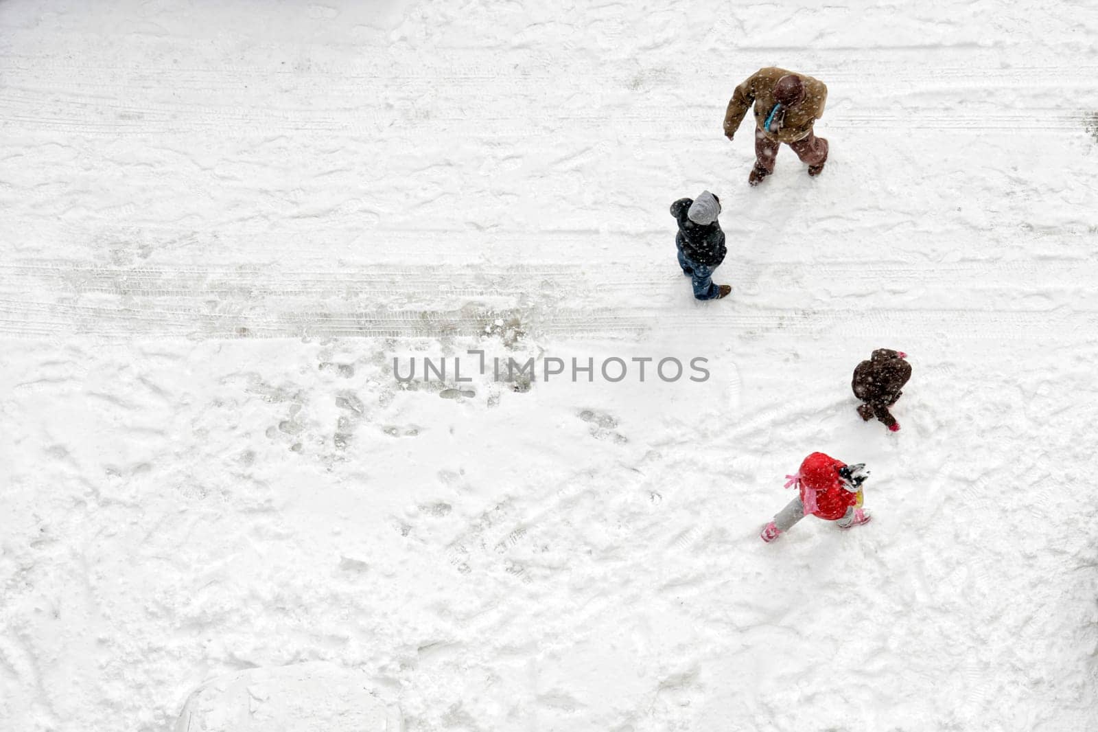 Elevated view of family play in snow covered parking lot