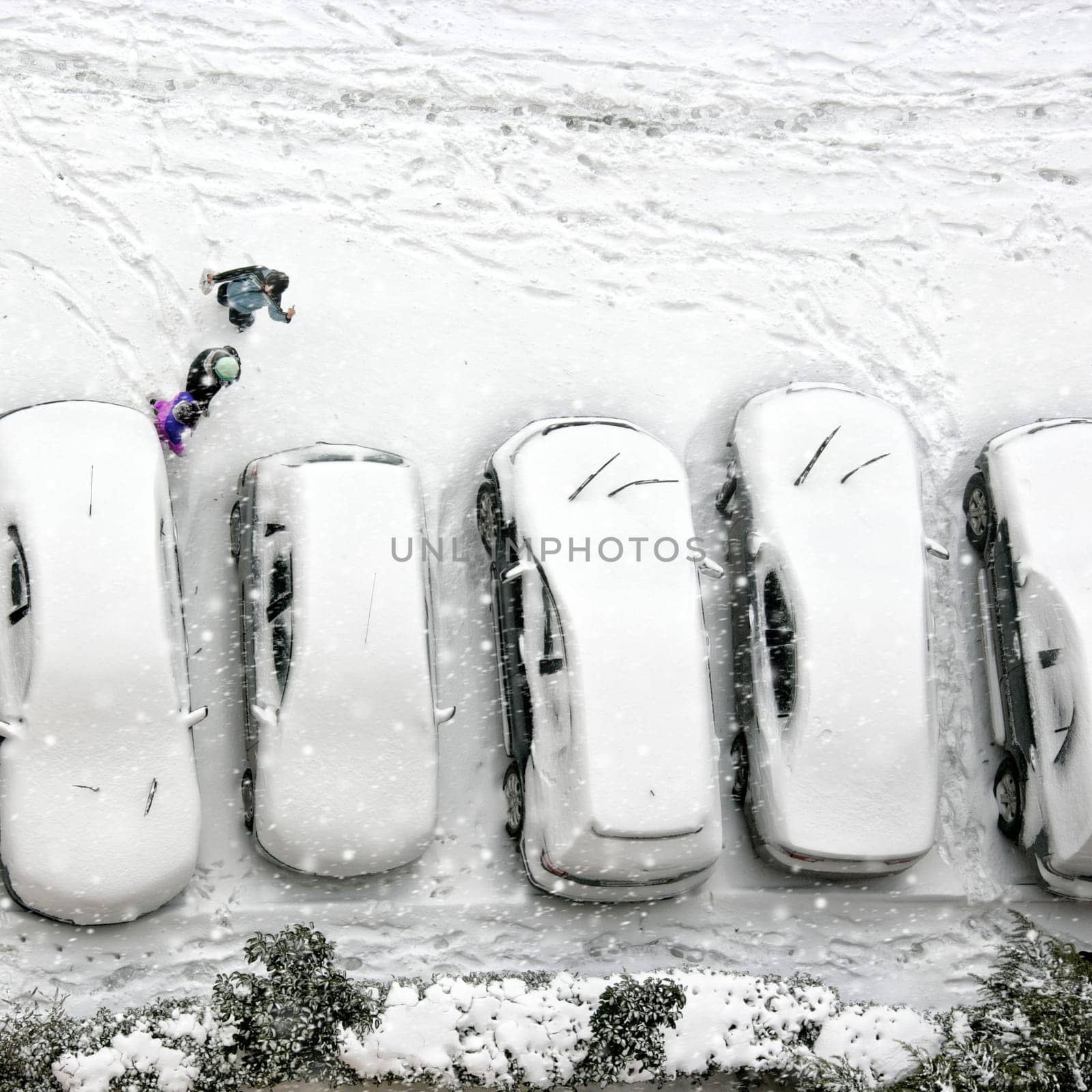 Elevated view of children play in snow covered parking lot